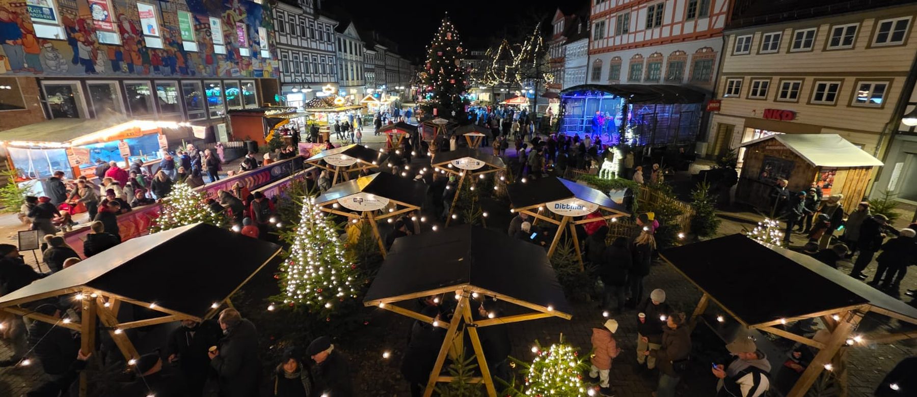 Der ganze Kornmarkt am Abend: Lichterbäume, Stehtische unter Schirmen und viele Besucher zwischen den Fachwerkhäusern